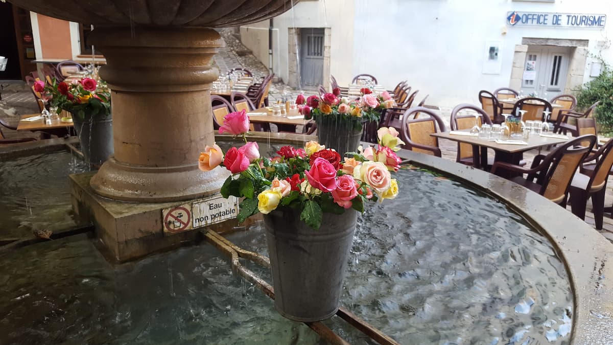 detail d'une fontaine agrementee d'un bouquet de fleurs dans le village de seillans dans le var