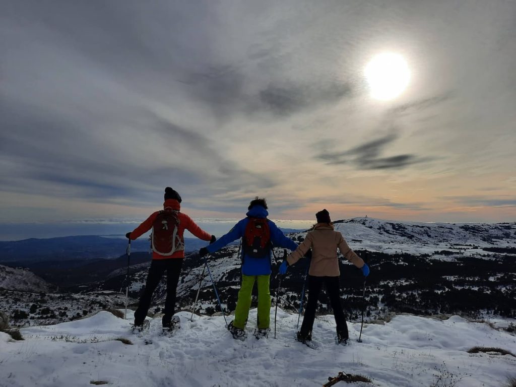 trois amis de dos en raquettes profitent du paysage du plateau de calern sur la commune de caussols