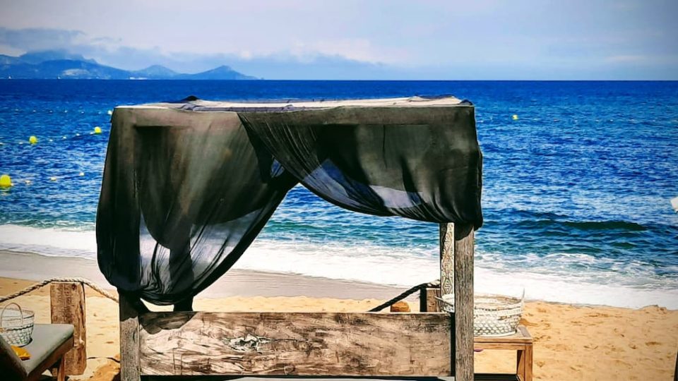 Un lit de plage avec une voile foncée au vent face à la mer, sur la plage Maiva à Roquebrune dans le Var