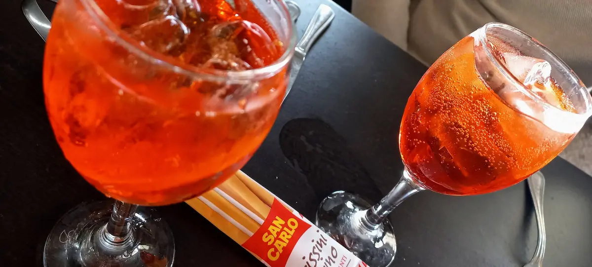 table de restaurant avec 2 verres de spritz fraichement servis et un sachet de gressins