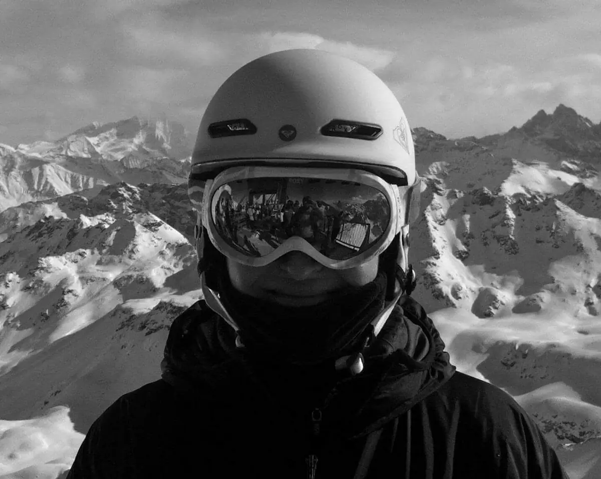 portrait d'une skieuse casquee en noir et blanc avec une chaine de montagne derriere elle, prise a verbier en suisse