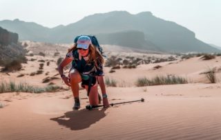 photo d'une trekkeuse genou a terre eclatant de rire dans le desert mauritanien en janvier 2023 lors d'un voyage avec allibert et isabelle fabre
