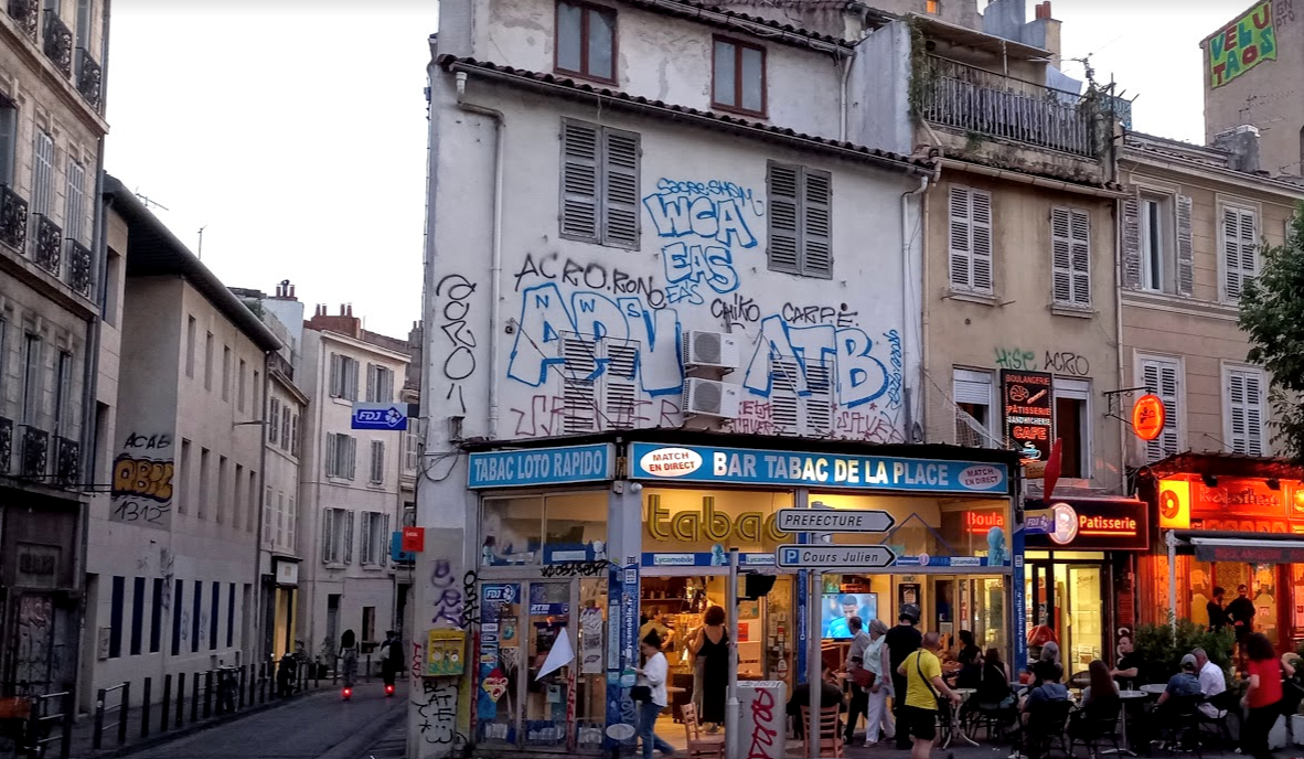visiter marseille en un weekend, c'est passer dans des quartiers moins glamour comme ce bar-tabac anime dans une rue populaire parsemee de graffiti