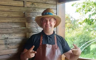 frederic bouteille fondateur de la fabrique tropicale pose devant un brasero avec un tablier en cuir