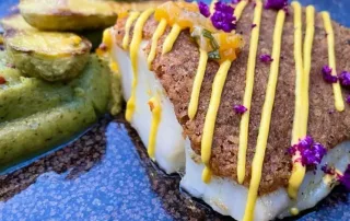 plat haut de gamme au restaurant la Garoupe représentant une assiette de poisson, légumes avec coulis et fleurs mangeables
