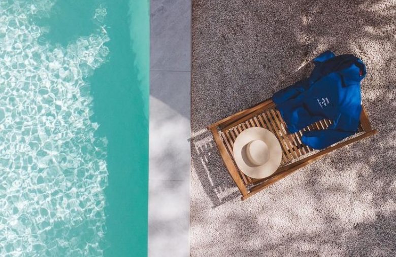 transat en bois sur lequel est pose un chapeau en paille et une chemise siglee hotel le sud au bord de la piscine qui est aussi ouverte aux personnes exterieures midi et soir pour deguster une pizza au food truck la cambrousse a juan les pins sur la cote d'azur