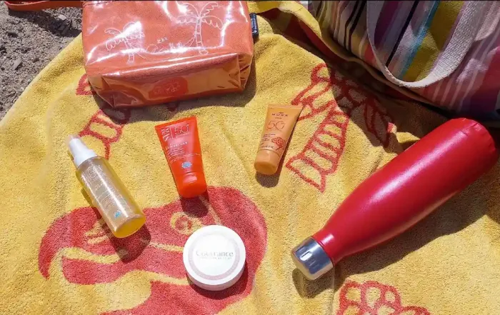 medley de produits solaires posés sur une serviette a la plage