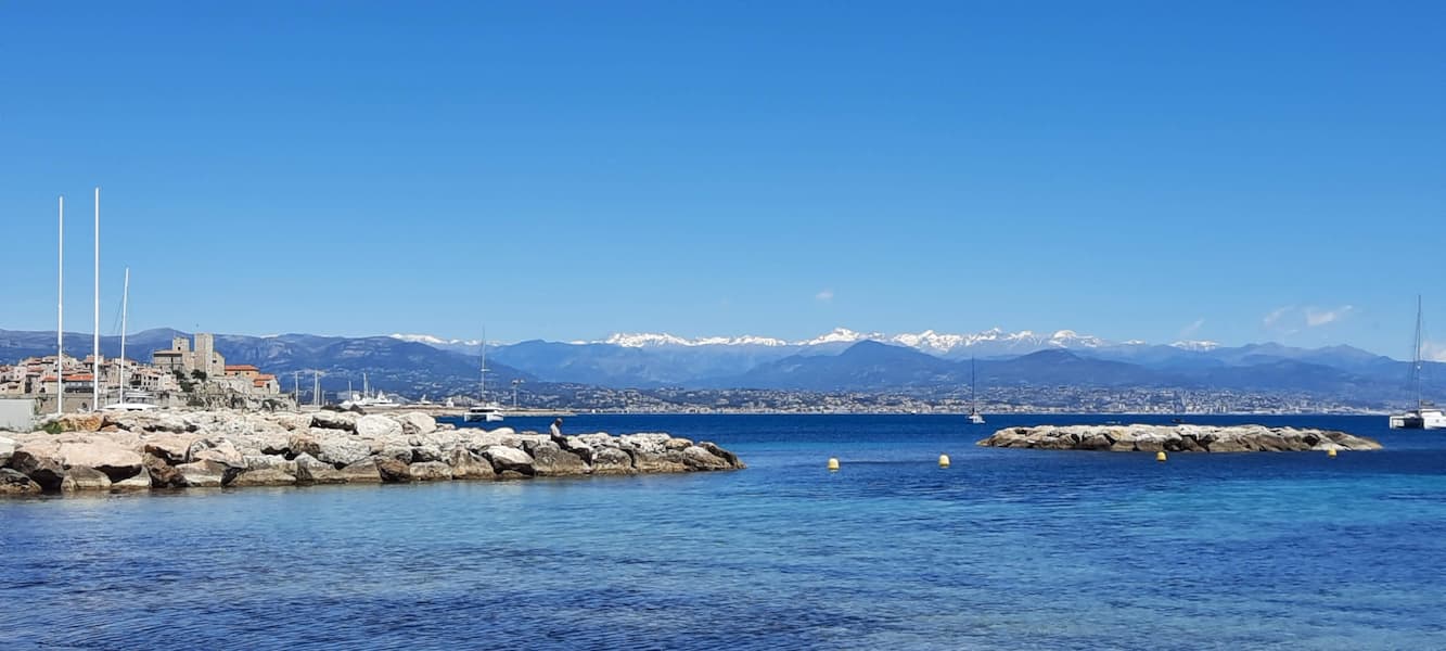 La Plage de la Salis à Antibes sur la Côte d'Azur avec ses sommets enneigés au loin